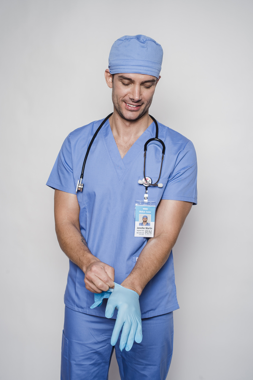de uniforme azul, auxiliar de enfermagem coloca luvas cirúrgicas nas mãos